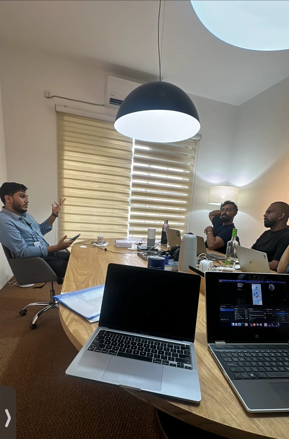 A participant walks through the new app on a phone while the team listens across the table.